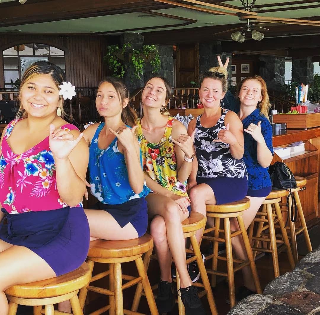 Five friends in aloha wear throwing shakas at the Harbor House bar