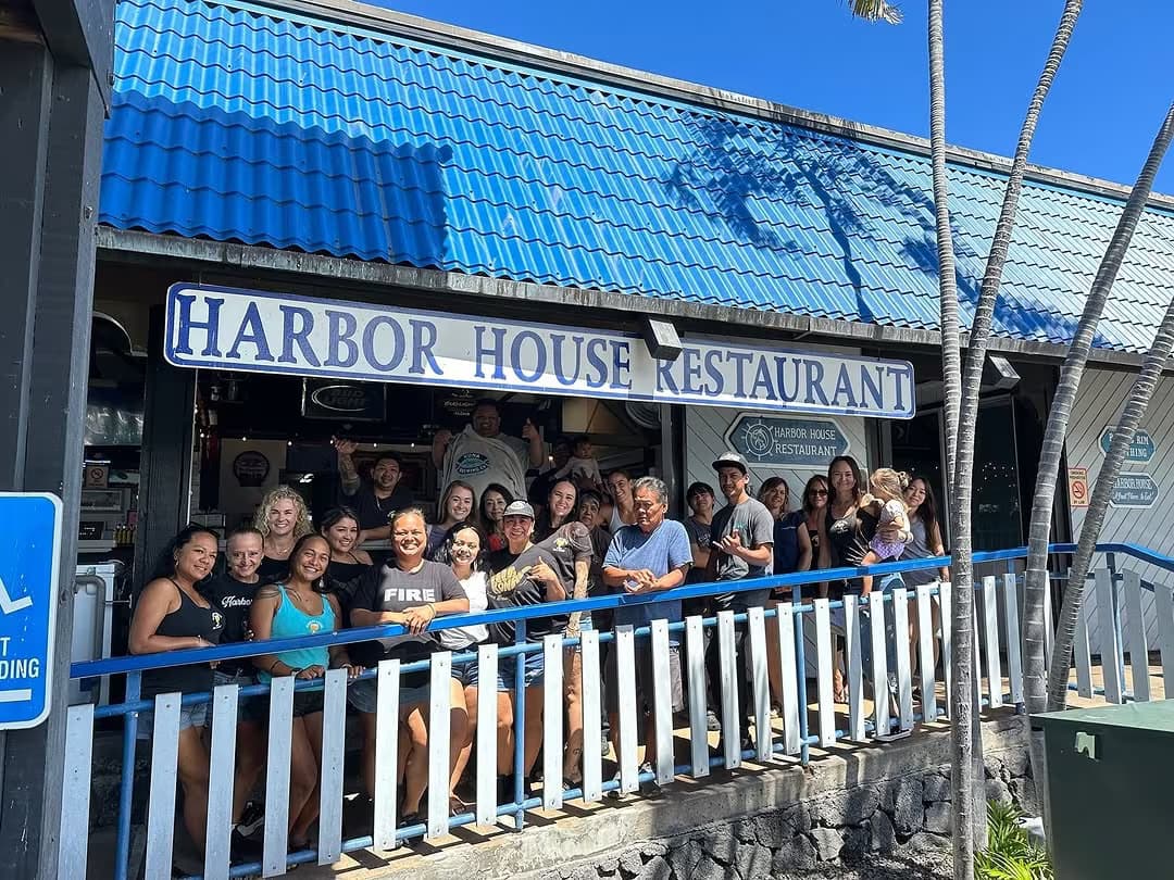 A full group of guests gathered under the Harbor House Restaurant sign in Kona