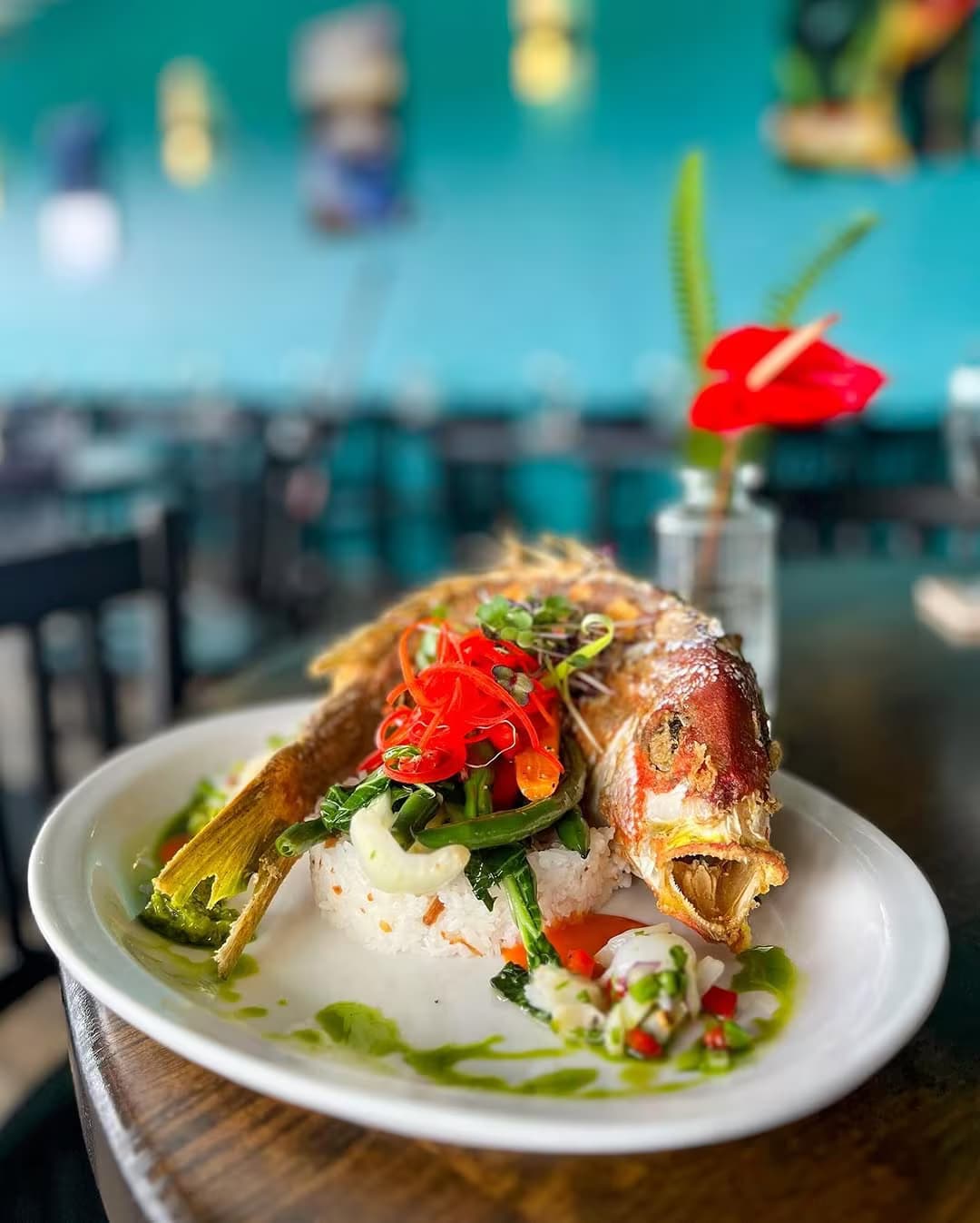 A whole Hawaiian fried fish plated with rice and shaved vegetables in Umeke's dining room